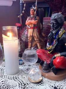 Bóveda with statues of Indian and Congo spirits, glass of water, candle, and crystal ball.